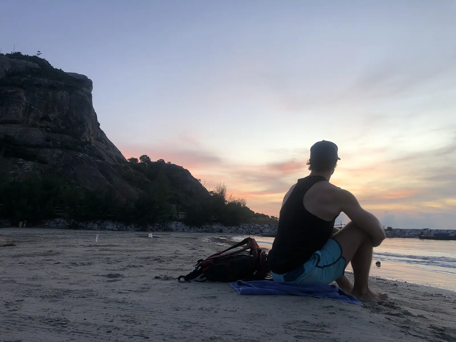 Sjoerd sitting on the beach at dusk, looking out at the sea and the mountain